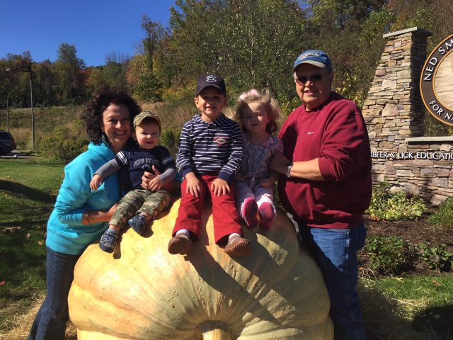ralph snyder and his wife with their grandkids sitting on a giant pumpkin