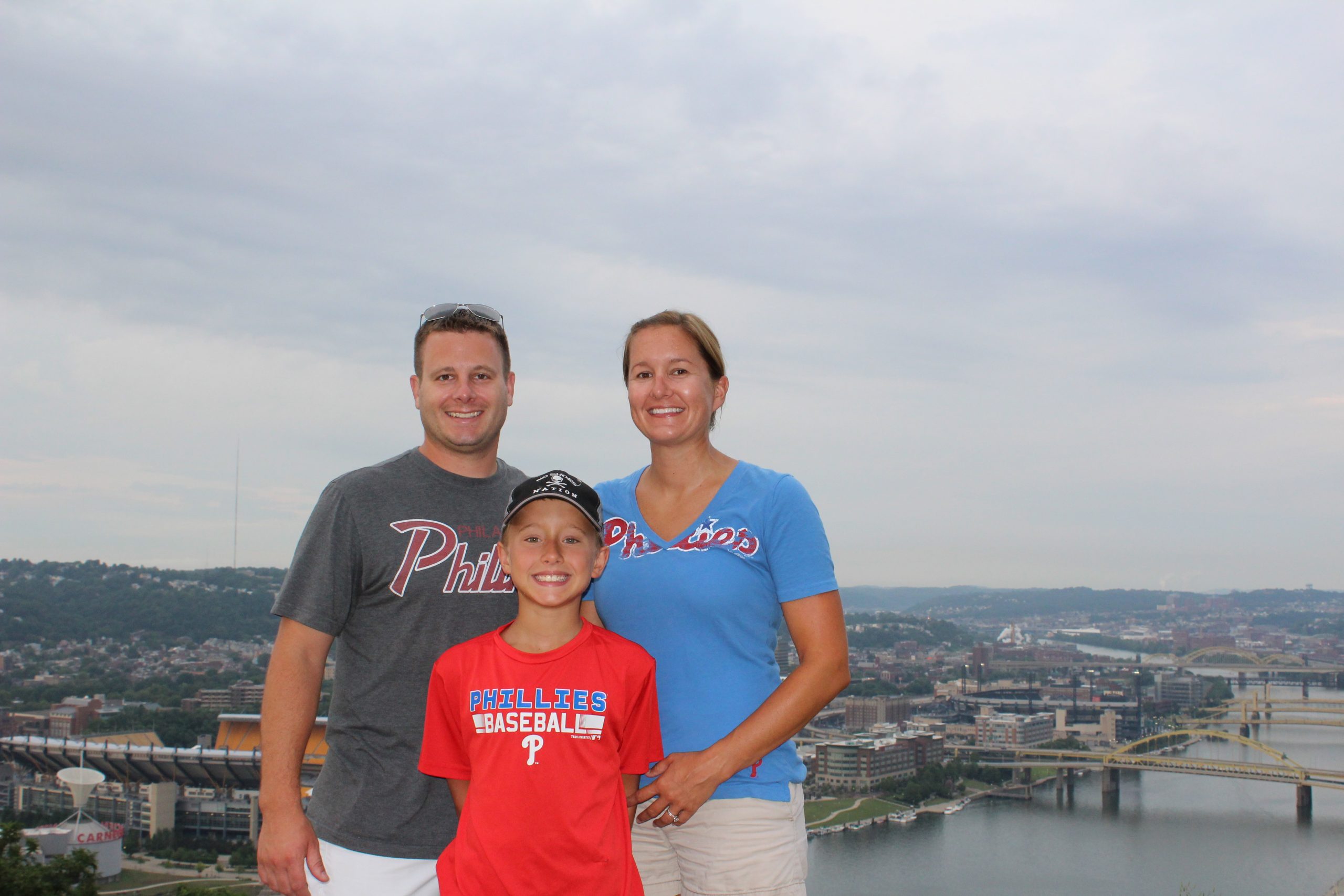 Shana Matz and her husband and son wearing Phillies shirts standing above Pittsburgh and Heinz Stadium