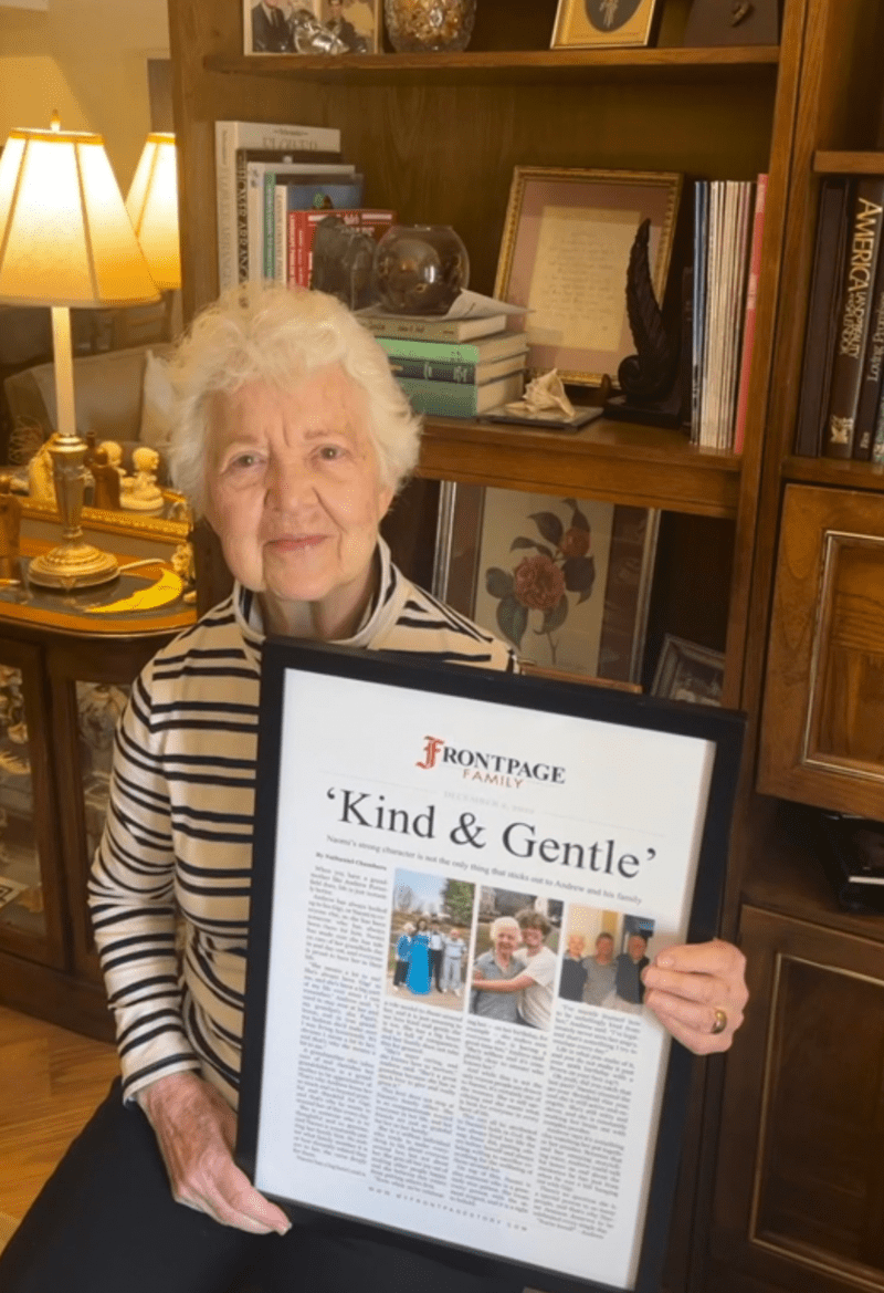 a woman holding a framed story titled 'Kind & Gentle'