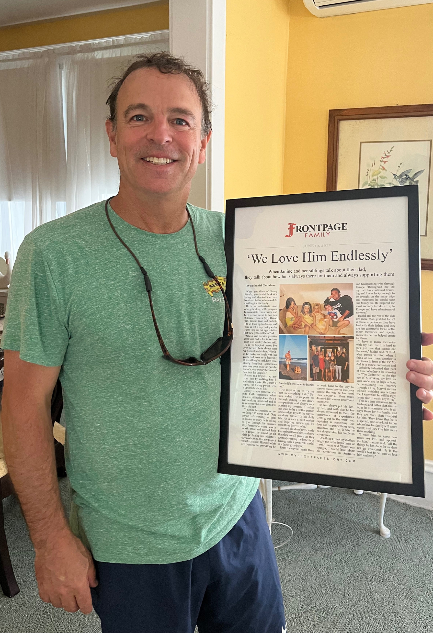 a man holding a framed story titled 'We Love Him Endlessly'