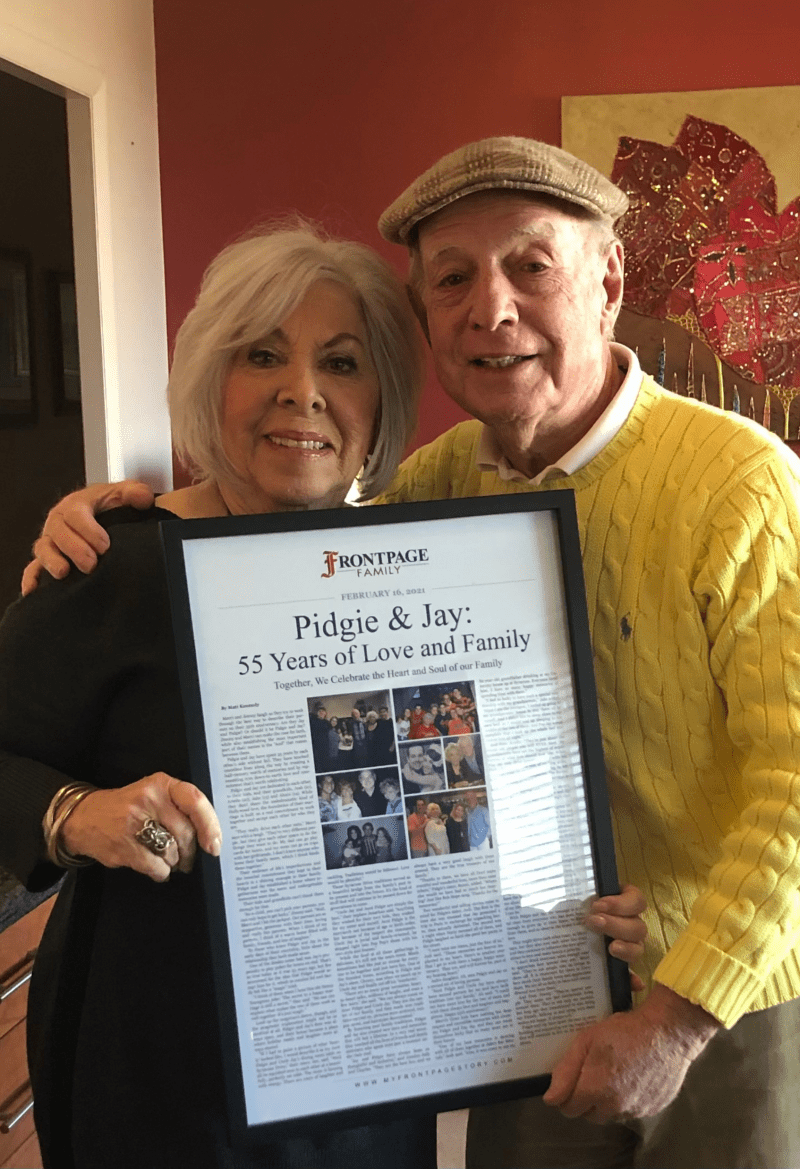 a husband and wife couple holding a framed story titled 'Pidgie & Jay: 55 Years of Love and Family'