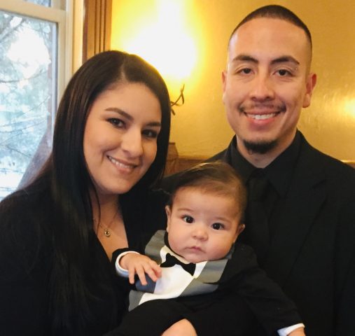 Sunnie and Andrew Andasola holding their son while all dressed up