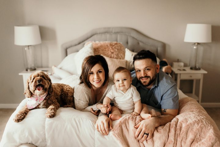Brandy and Jeff Miller with their child and dog at the edge of their bed
