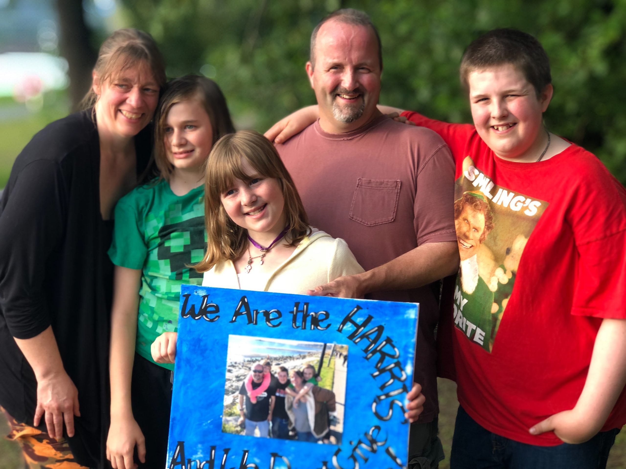 Cheryl Harris with her husband, son and two daughters holding a picture while taking a picture