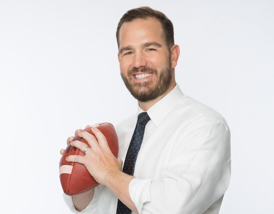 Sports podcasting legend Ross Tucker holding a football like a quarterback