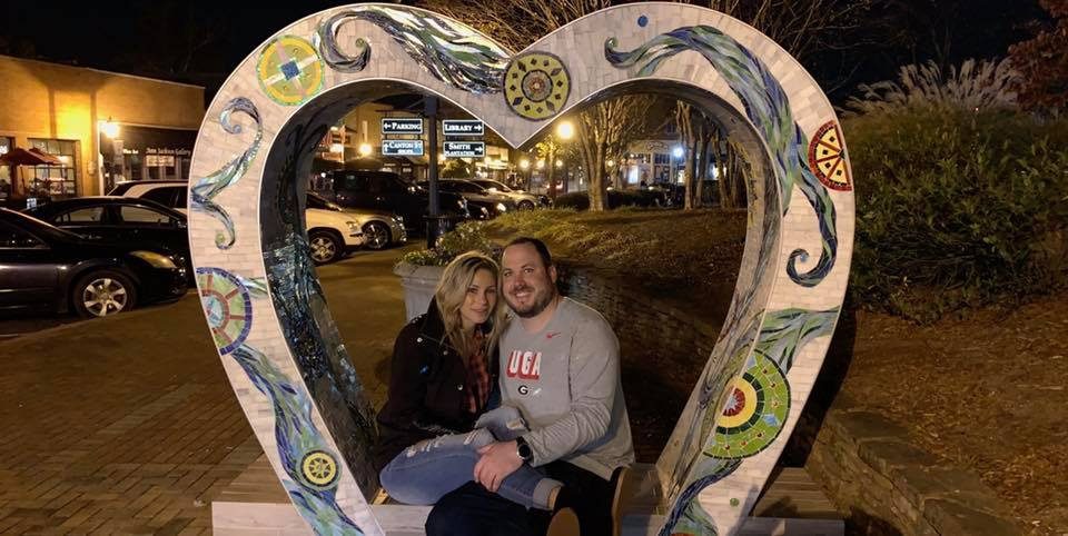 Chasity Miller with her boyfriend sitting in a heart sculpture