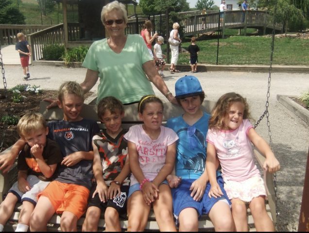 Barb Hedrick with all her grandkids on the swinging park bench