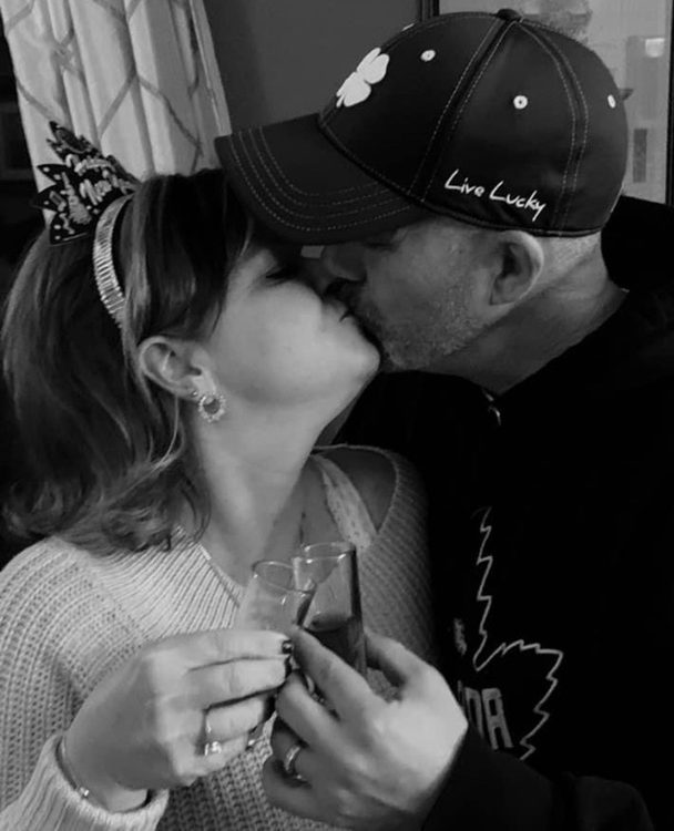 Donna Firth and her husband kissing while cheering with shot glasses