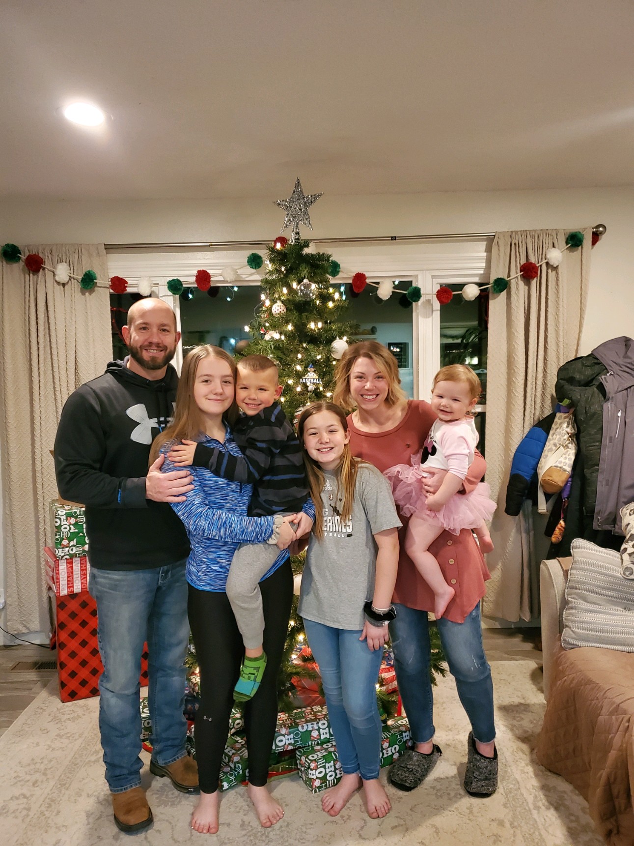 Kate and her family in front of the Christmas tree with presents under it