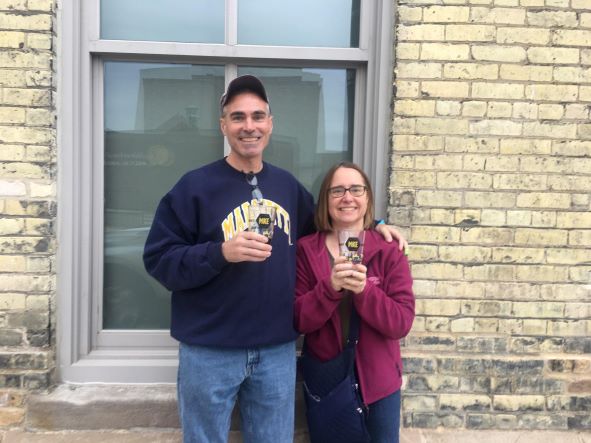 Terry Stadler and his wife in sweatshirts holding up their matching glasses of drink