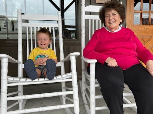 Dee Dee (Winona Chambers) and her great grandson sitting on white rocking chairs
