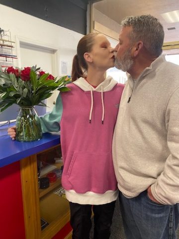 Laurie Longfellow with her husband James kissing in sweatshirts