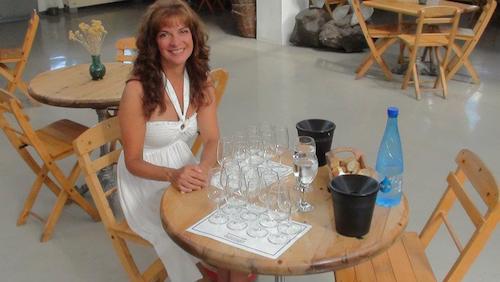 Karen Yackel sitting at a table with a bunch of empty wine glasses in front of her