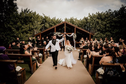 Nick and Liz Nuño walking past their guests at their outdoor wedding right after tying the knot