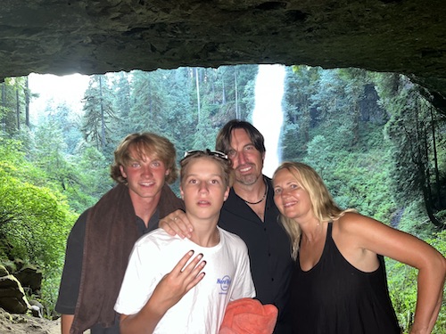 Melody Wright with her husband and children in a cave in front of a waterfall and forrest