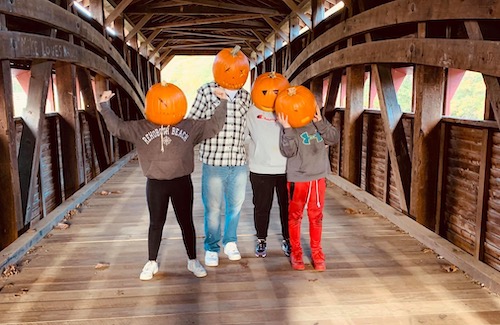 Shelly's clan wearing pumpkin heads on a bridge