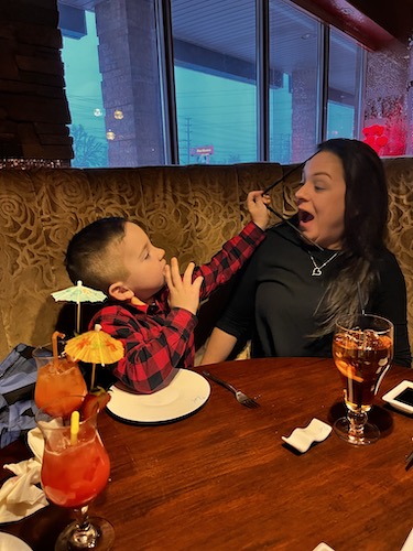 Bobbi making a facial reaction to her son putting his straw in her face