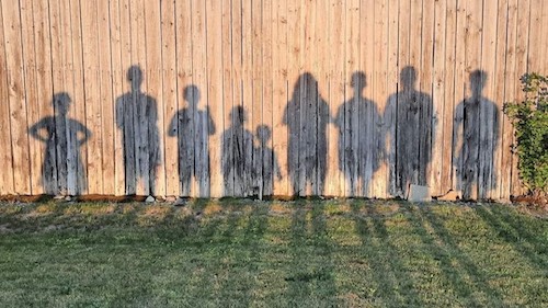 Gillman family silhouette shadows against the fence