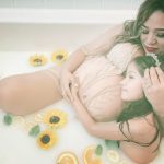 Vania sitting pregnant in the tub with her daughter with milk and flowers and oranges