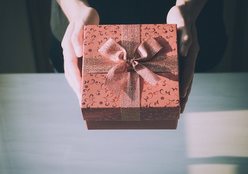 Person offering a present wrapped with a bow