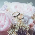 a pair of wedding bands sitting on top of light pink roses