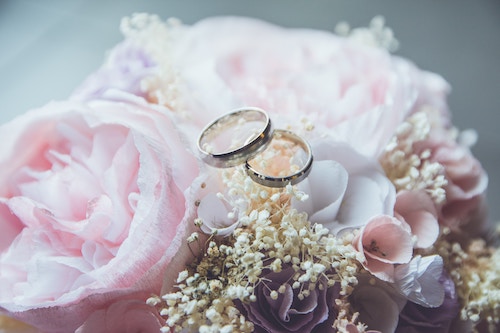a pair of wedding bands sitting on top of light pink roses