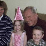 Michael L Bundy smiling with his wife and grandchildren