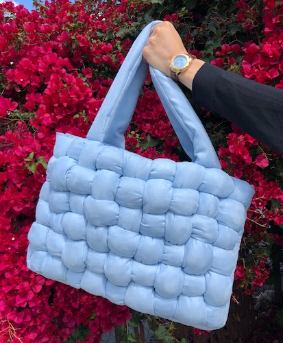 custom baby blue crochet bag held in front of a red leaf tree