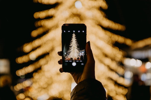 snapping a picture of someone snapping a picture of a Christmas tree