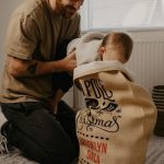 man helping baby open Santa sack