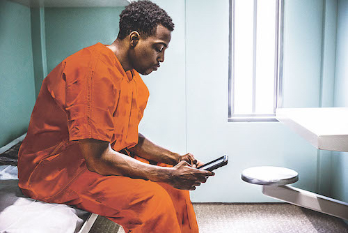 And incarcerated inmate scrolling through his phone in his jail cell