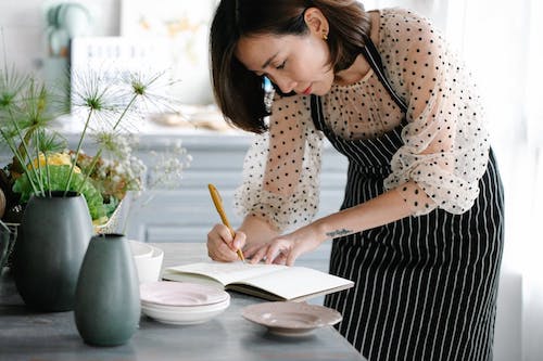 A woman writing down a recipe.